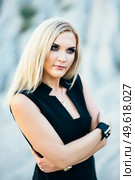 blonde girl in a black trouser suit with blue eyes on the background of a granite quarry from gray rubble. Стоковое фото, агентство Ingram Publishing / Фотобанк Лори