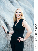blonde girl in a black trouser suit with blue eyes on the background of a granite quarry from gray rubble. Стоковое фото, агентство Ingram Publishing / Фотобанк Лори