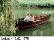 a boat trip for a guy and a girl along the canals and bays of the river overgrown with wild willows. Стоковое фото, агентство Ingram Publishing / Фотобанк Лори