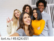 Multi-ethnic group of friends taking a selfie together while having fun in the street. Caucasian girl in the foreground.. Multi-ethnic group of friends taking a selfie together while having fun outdoors. Стоковое фото, агентство Ingram Publishing / Фотобанк Лори