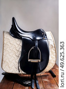 Black professional  leather dressage saddle in complete with nice saddle cloth and girth puted at saddle rack travel. equestrian concept. Стоковое фото, агентство Ingram Publishing / Фотобанк Лори