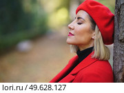 Close-up profile picture of a middle-aged woman leaning against a tree trunk with her eyes closed. Female in beret and red coat taking time to relax.. Close-up profile picture of a middle-aged woman leaning against a tree trunk with her eyes closed. Стоковое фото, агентство Ingram Publishing / Фотобанк Лори