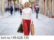 Attractive middle-aged woman shopping in a shopping street carrying bags with what she has bought.. Middle-aged woman shopping in a shopping street carrying bags with what she has bought. Стоковое фото, агентство Ingram Publishing / Фотобанк Лори
