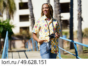 Happy young black female combed with colorful braids walking with a camera on vacation.. Happy black female combed with colorful braids walking with a camera on vacation. Стоковое фото, агентство Ingram Publishing / Фотобанк Лори