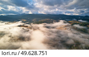 Colorful autumn morning over foggy mountain valley. Village covered by low clouds. Fall rural landscape. Misty cold November morning. Carpathians range, Ukraine, Europe. Стоковое фото, агентство Ingram Publishing / Фотобанк Лори