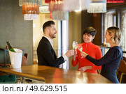 Company of cheerful friendly people in elegant outfits clicking glasses with champagne and proposing toast while celebrating event in restaurant. Group of friends clicking glasses in bar. Стоковое фото, агентство Ingram Publishing / Фотобанк Лори