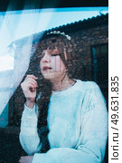 Sad woman alone in her home looking through a window in a rainy day. Стоковое фото, агентство Ingram Publishing / Фотобанк Лори