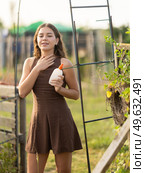 Young girl spraying mosquito repellent on herself on summer day at farm. Стоковое фото, фотограф Яков Филимонов / Фотобанк Лори