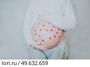 Young happy mom with a lot of red hearts in her tummy. Стоковое фото, агентство Ingram Publishing / Фотобанк Лори