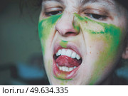 Angry young woman with her face painted with green dust. Стоковое фото, агентство Ingram Publishing / Фотобанк Лори