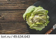 Close up of whole raw cauliflower on black cutting board with knife at rustic wooden kitchen table. Healthy uncooked garden vegetable. Cooking preparation. Top view. Стоковое фото, агентство Ingram Publishing / Фотобанк Лори