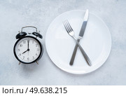 Intermitted farsting diet concept - empty plate with fork and knife and timer. Intermitted farsting diet concept. Стоковое фото, агентство Ingram Publishing / Фотобанк Лори