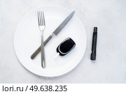 Diabetes diet planning concept, empty plate with fork, knife and glukemetr, fasting diet and dieabetes sugar level control equipment. Diabetes diet planning concept. Стоковое фото, агентство Ingram Publishing / Фотобанк Лори