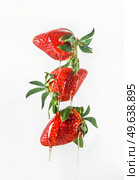Honey dripping from flying red strawberries at white background. Delicious healthy sweet food levitating in the air. Liquid and fruit.  Front view. Стоковое фото, агентство Ingram Publishing / Фотобанк Лори