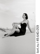 girl in a black long dress in a sandy desert under a blue sky. Стоковое фото, агентство Ingram Publishing / Фотобанк Лори