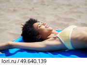 Smiling black woman lying on the sand of a tropical beach sunbathing. African American girl tanning.. Smiling black woman lying on the sand of a tropical beach sunbathing. Стоковое фото, агентство Ingram Publishing / Фотобанк Лори