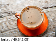 fresh boiled coffee served in beautiful orange cup around old style wooden background . close up. flat lay . Стоковое фото, агентство Ingram Publishing / Фотобанк Лори