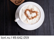 porcelain cup of coffee with ice cream and cinnamon heart served  at black wooden table. Стоковое фото, агентство Ingram Publishing / Фотобанк Лори