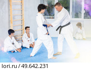 Male karate instructor training little child wearing kimono in dojo or jiu-jitsu in gym. Стоковое фото, фотограф Яков Филимонов / Фотобанк Лори