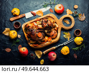Pork knuckle or shank grilled with apples on cutting board. Roasted meat with autumn fruits. Стоковое фото, агентство Ingram Publishing / Фотобанк Лори