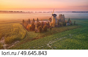 Traditional Wooden Windmill Morning Landscape. Rural colorful Sunrise, Foggy green fields. Dudutki village, Minsk Region, Belarus. Стоковое фото, агентство Ingram Publishing / Фотобанк Лори