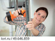 beautiful young brown-hair woman in plaid drilling. Стоковое фото, агентство Ingram Publishing / Фотобанк Лори