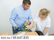 health professional in training using cardiac defibrillator to dummy. Стоковое фото, агентство Ingram Publishing / Фотобанк Лори