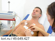 Nurse attaching heart monitor pads to man's chest. Стоковое фото, агентство Ingram Publishing / Фотобанк Лори