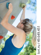 beautiful young woman starts to climbing big artificial wall. Стоковое фото, агентство Ingram Publishing / Фотобанк Лори