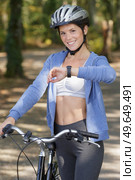 bicyclist girl looking at watch on smart watch. Стоковое фото, агентство Ingram Publishing / Фотобанк Лори