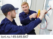 apprentice electrician using a multimeter on a fusebox. Стоковое фото, агентство Ingram Publishing / Фотобанк Лори