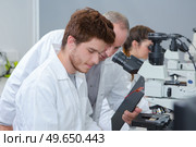 young male medical researcher looking through microscope. Стоковое фото, агентство Ingram Publishing / Фотобанк Лори