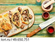 Closed homemade mushroom pie. Sliced savoury mushroom champignons pie on old kitchen board. Seasonal traditional mushroom pie. Стоковое фото, агентство Ingram Publishing / Фотобанк Лори
