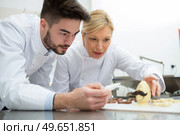 apprentice and confectioner working in chocolate factory. Стоковое фото, агентство Ingram Publishing / Фотобанк Лори