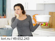 woman holding a bucket while water droplets leaking from ceiling. Стоковое фото, агентство Ingram Publishing / Фотобанк Лори