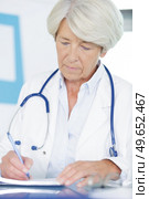 portrait of female doctor writing on clipboard. Стоковое фото, агентство Ingram Publishing / Фотобанк Лори