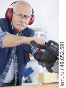 senior man wearing ear protectors while using circular saw. Стоковое фото, агентство Ingram Publishing / Фотобанк Лори
