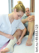 young female doctor is bandaging a male patient. Стоковое фото, агентство Ingram Publishing / Фотобанк Лори