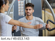 gym trainer showing right position to use gym machine. Стоковое фото, агентство Ingram Publishing / Фотобанк Лори