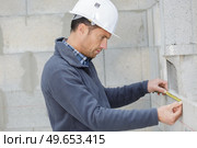 worker checks erected brick wall with level. Стоковое фото, агентство Ingram Publishing / Фотобанк Лори