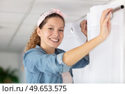beautiful woman in the house hangs curtains. Стоковое фото, агентство Ingram Publishing / Фотобанк Лори