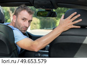 man looking over his shoulder while reversing. Стоковое фото, агентство Ingram Publishing / Фотобанк Лори