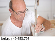 plumber fixing tap in bathroom. Стоковое фото, агентство Ingram Publishing / Фотобанк Лори