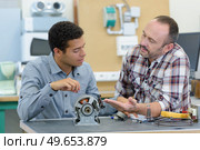 male mechanics looking at dismantled magneto. Стоковое фото, агентство Ingram Publishing / Фотобанк Лори