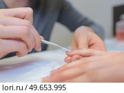 close up of professional manicurist using cuticle pusher doing manicure. Стоковое фото, агентство Ingram Publishing / Фотобанк Лори