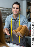 craftsman giving boots to female customer. Стоковое фото, агентство Ingram Publishing / Фотобанк Лори