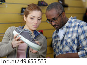 couple deciding on new sneakers in sports equipment store. Стоковое фото, агентство Ingram Publishing / Фотобанк Лори