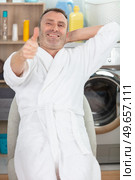 man in utility room wearing dressing gown showing thumbs up. Стоковое фото, агентство Ingram Publishing / Фотобанк Лори