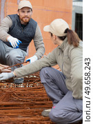 male and female construction workers using metal reinforcement bars. Стоковое фото, агентство Ingram Publishing / Фотобанк Лори