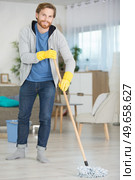 cheerful young man mopping the floor at home. Стоковое фото, агентство Ingram Publishing / Фотобанк Лори